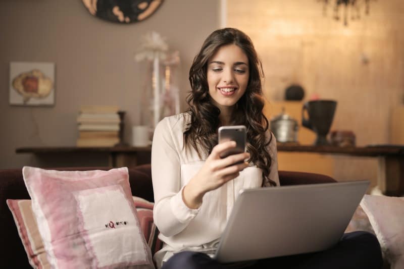 woman sitting on sofa while looking at phone